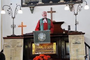 Rev. Colin Richards during the Reunion Service, with the 1860s Colliery scrolls either side of the pulpit